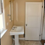 sink. A vintage etched glass mirror and marble floor tiles complement the room.