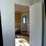 To the right is a swing door into the dining room and a view of the entry hall.
